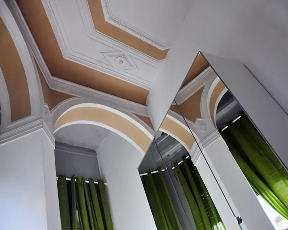 Immagine focalizzata su archi decorativi del soffitto e un armadio con specchio; la foto mette in evidenza dettagli architettonici più che la funzione di una stanza specifica.