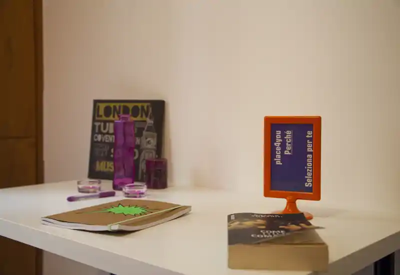 Small bedside/worktable scene with decorative items, a notebook and books on a white surface — suitable as a detail shot of a bedroom or bedside table.