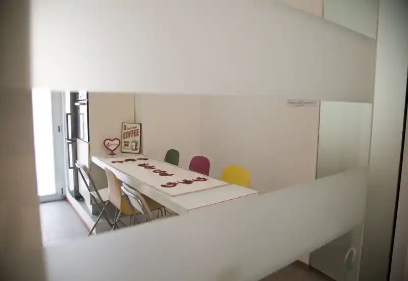 Bright, modern dining space with a long white table, colorful chairs and decorative runner — ideal for casual meals and gatherings.