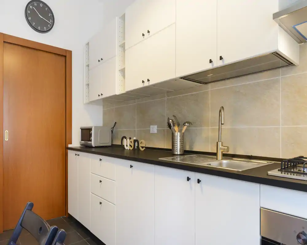 Modern, well-lit kitchen with white cabinets, a sink, gas hob and tasteful decorative accents providing a clean and functional cooking space.