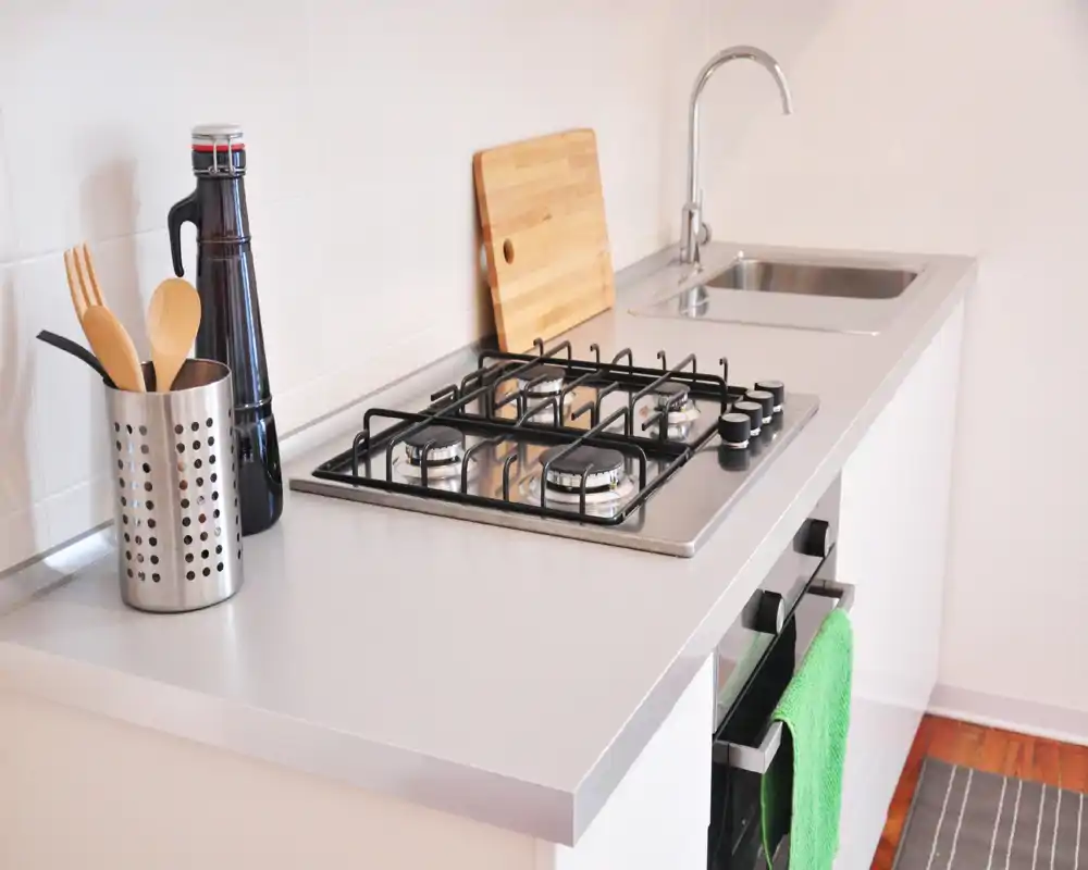 Cucina moderna e luminosa con piano cottura a gas in acciaio, lavello e pochi accessori sul piano — spazio funzionale e curato, ideale per affitti brevi.