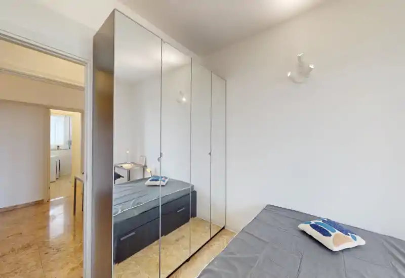 Small bedroom with a single bed, mirrored wardrobe and neutral decor. The room is bright and simply furnished, suitable for a rental listing showing storage and sleeping area.