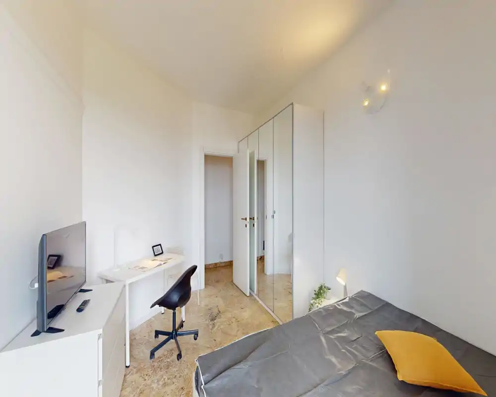 Camera da letto luminosa e minimale con letto matrimoniale, armadio con ante specchiate e una piccola scrivania — stile moderno e pulito ideale per una persona.