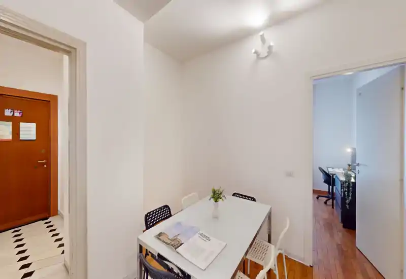 Petite salle à manger moderne avec table blanche, chaises assorties et un vase décoratif, lumineuse et bien rangée — idéale pour les annonces d'appartements compacts.