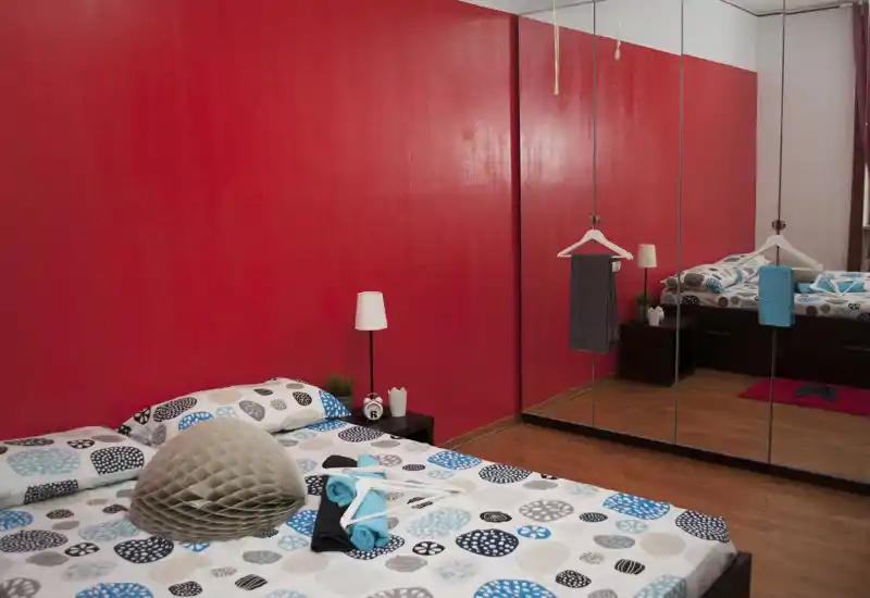 Dormitorio moderno y luminoso con ropa de cama estampada, mesita de noche y un gran armario con espejo que amplía el espacio.