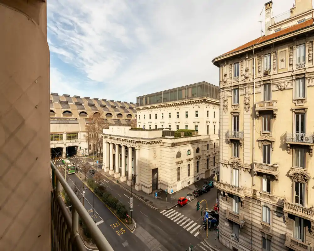 Balcón soleado con vistas a una calle histórica de la ciudad, edificios clásicos y cielo despejado — ideal para disfrutar de la luz de la mañana.