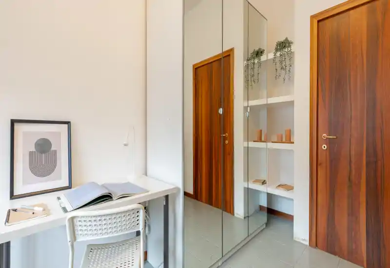 Petit hall d'entrée avec placard miroir, porte en bois et un petit bureau — lumineux, soigné et adapté pour un travail bref ou du rangement.