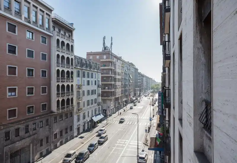Sunny street view from a balcony overlooking a broad urban avenue with parked cars and multi-story buildings, ideal to showcase location and surroundings.