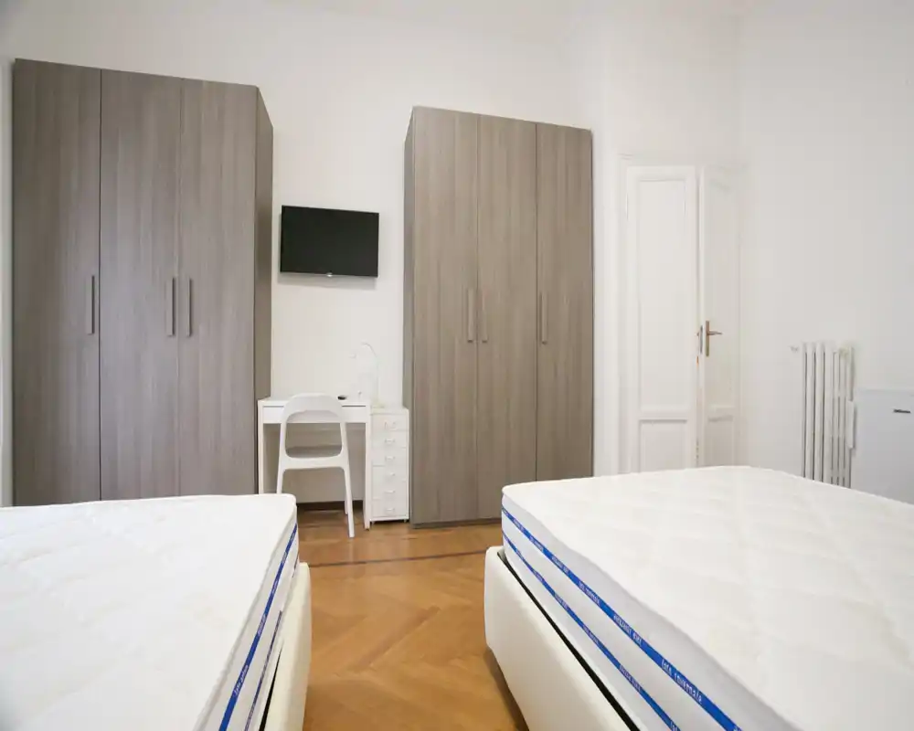 Dormitorio luminoso con dos colchones individuales, armarios modernos y un pequeño escritorio — limpio, minimalista y bien iluminado, ideal para anuncios de alquiler.