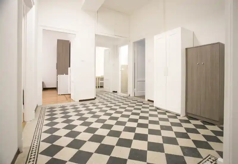 Ampio ingresso/corridoio con pavimento a piastrelle bianche e nere decorative, pareti bianche e armadietti: spazio di passaggio luminoso e accogliente.