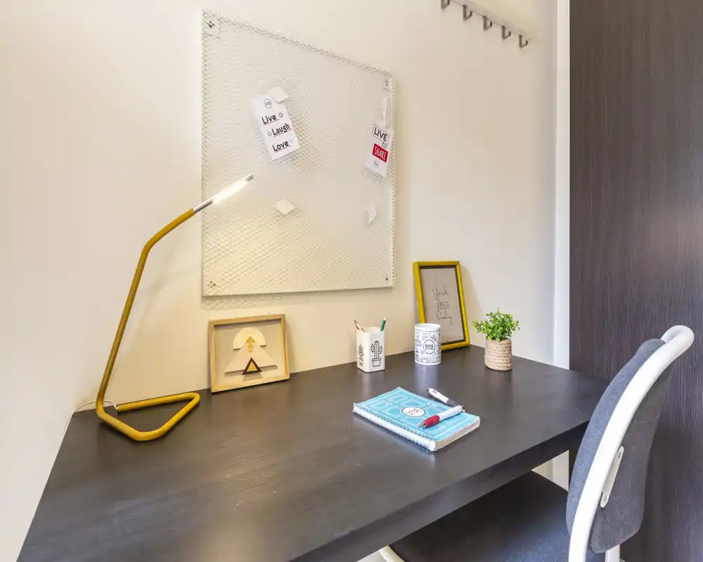Bright, tidy study nook with a dark wooden desk, modern yellow desk lamp, chair, small plant and pinboard — ideal for focused work or study.