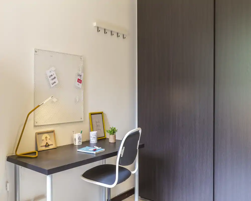 A tidy home office corner with a compact desk, chair, lamp, small plant and decorative items — ideal for focused work or study.