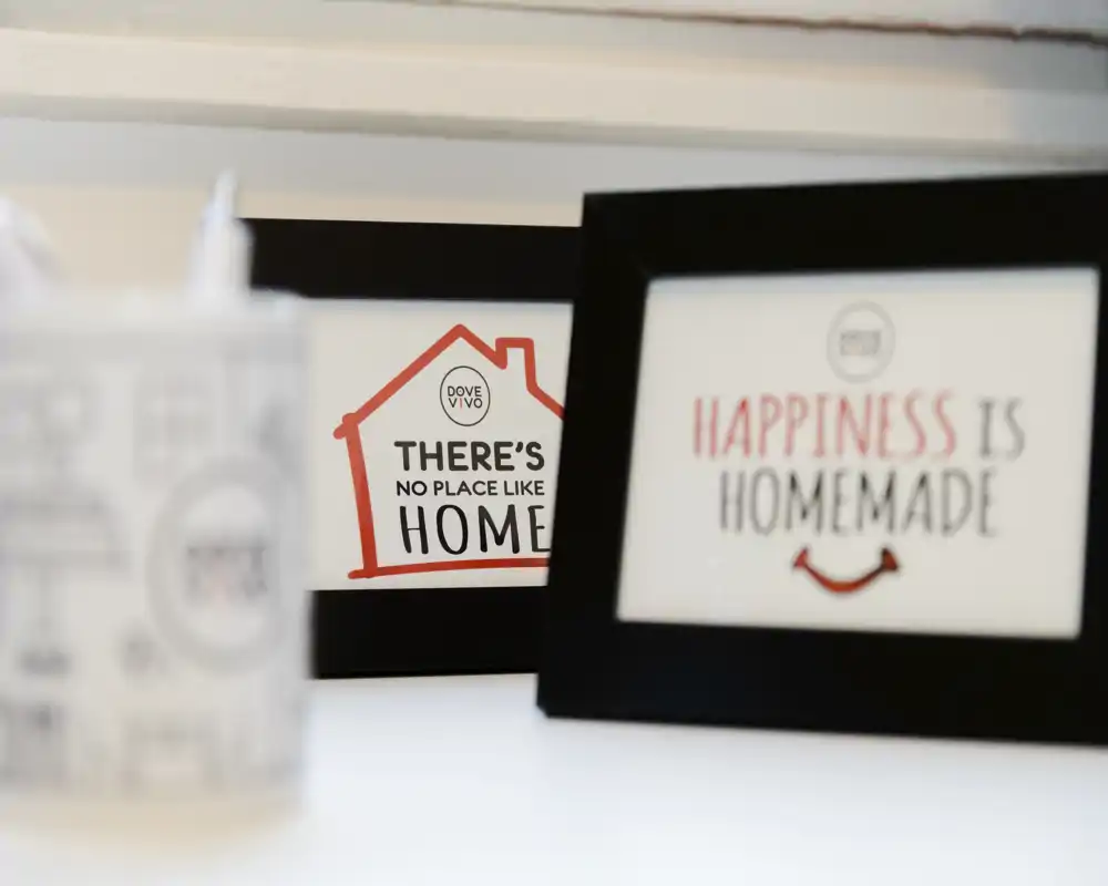 Close-up of decorative tabletop frames with positive messages (‘There’s no place like home’, ‘Happiness is homemade’). The photograph focuses on decor details rather than showing a full room.