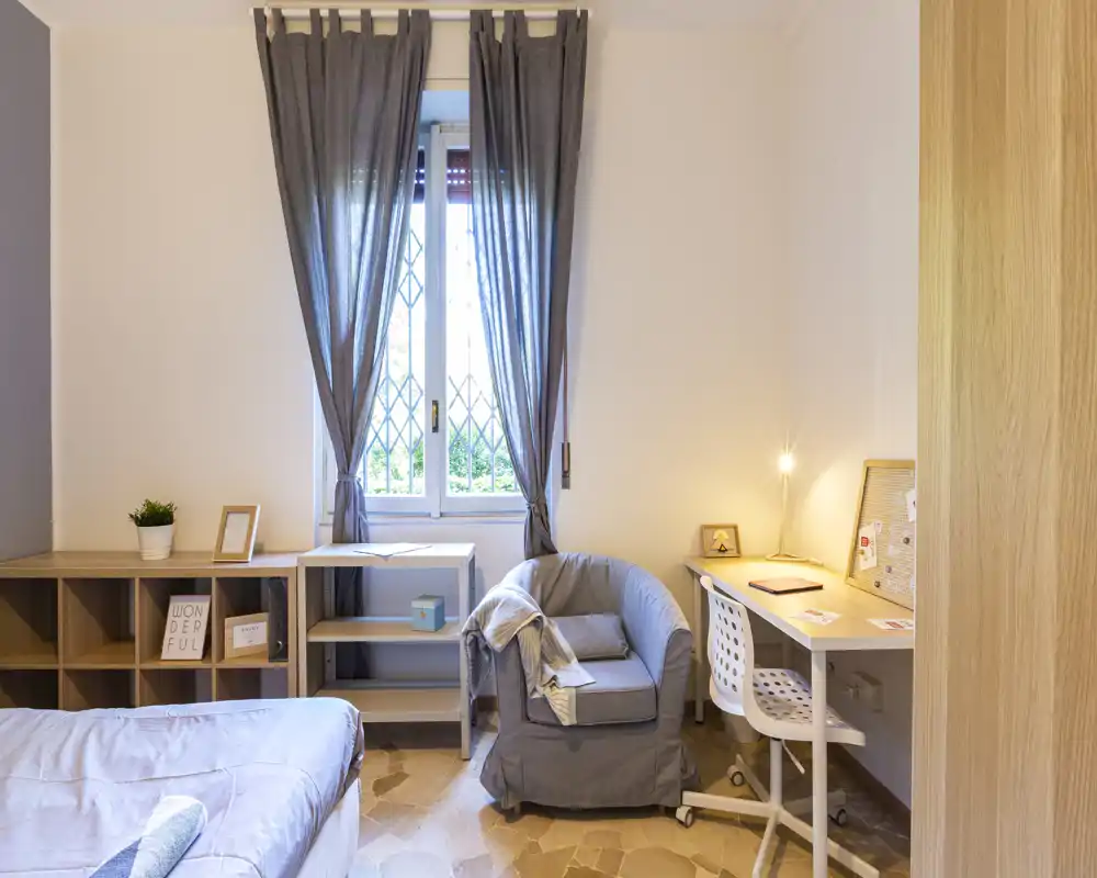 Bright, well-styled bedroom corner with a comfortable bed, armchair and a desk by the window — ideal for both rest and work.