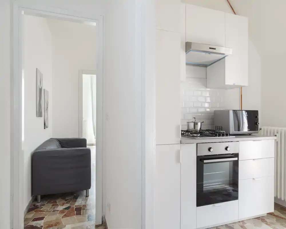 Compact modern kitchen with white cabinetry, gas stove and built-in oven; bright, clean layout ideal for a small apartment.