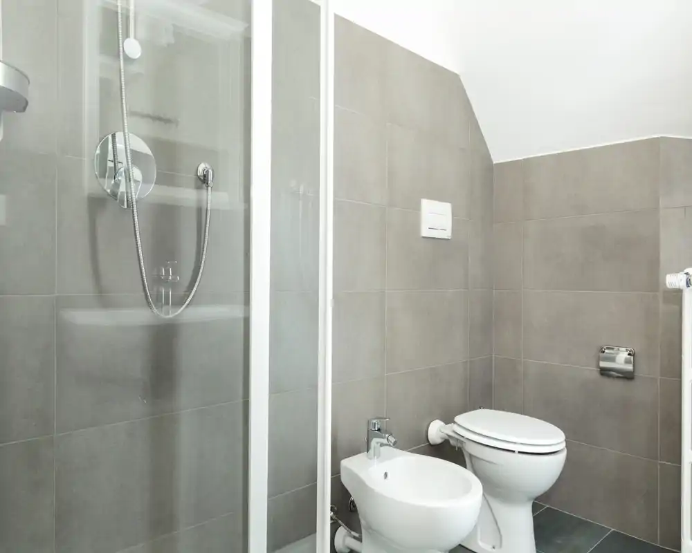 Bright, modern bathroom with tiled walls, glass shower enclosure, bidet and toilet — clean and minimal design ideal for listings.