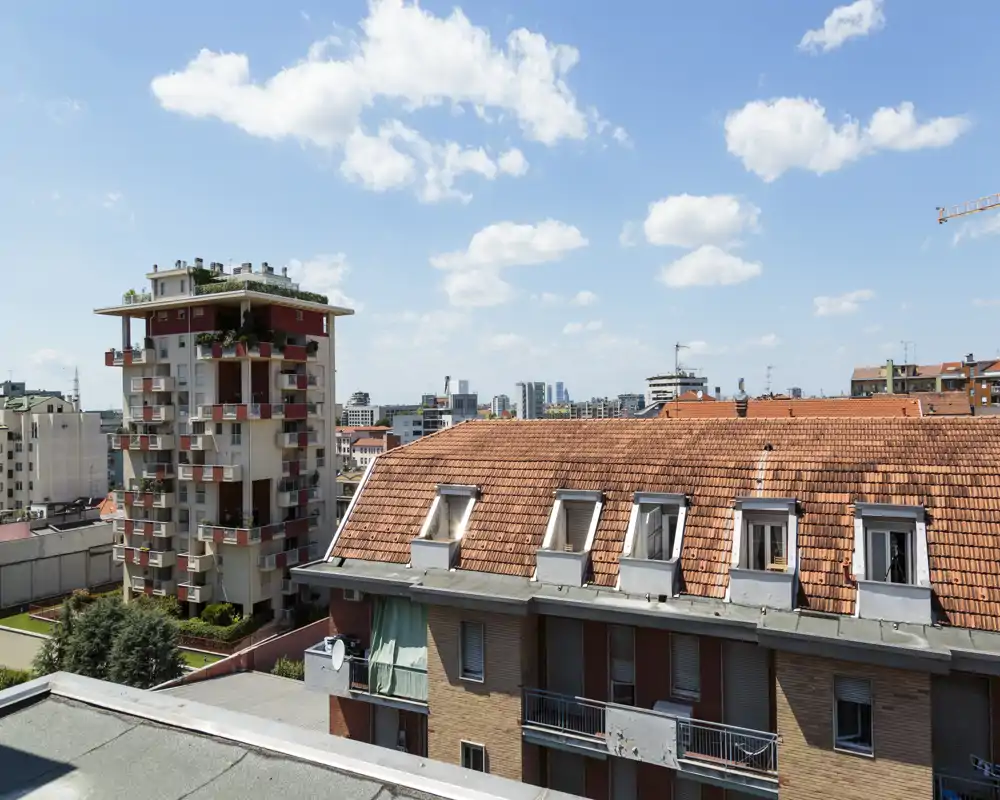 Sunny rooftop and city view showing neighboring buildings and a clear blue sky — ideal for highlighting views and location.