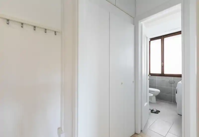 Bright entryway with built-in closets and a view into the adjacent bathroom; neutral decor and practical layout ideal for an apartment entrance.