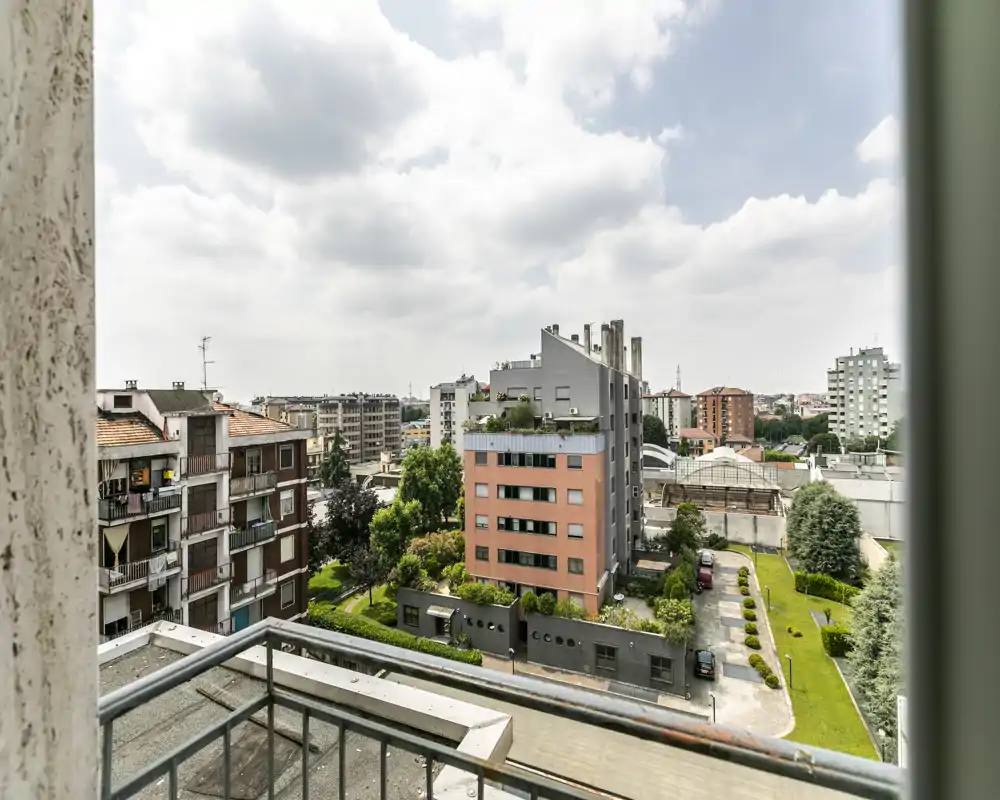 Balcone soleggiato con vista sugli edifici residenziali vicini, piccolo giardino e cortile — ideale per mostrare lo spazio esterno e i dintorni.