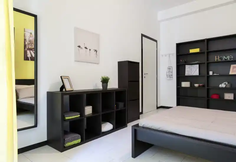 Camera da letto moderna e luminosa con letto basso, scaffalature aperte e decor minimalista — ben illuminata e ordinata per annunci di affitto.