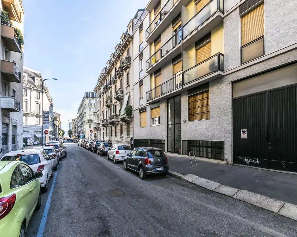 Vista exterior de una calle de la ciudad con coches aparcados a lo largo de una manzana residencial, mostrando las fachadas y la acera — útil para destacar la ubicación y el acceso en un anuncio.
