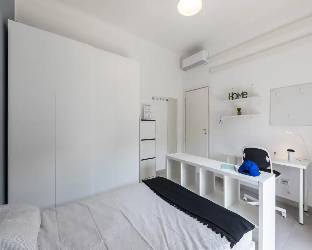 Dormitorio moderno y luminoso con cama ordenada, gran armario blanco y zona de estudio compacta — estilo minimalista ideal para el anuncio.