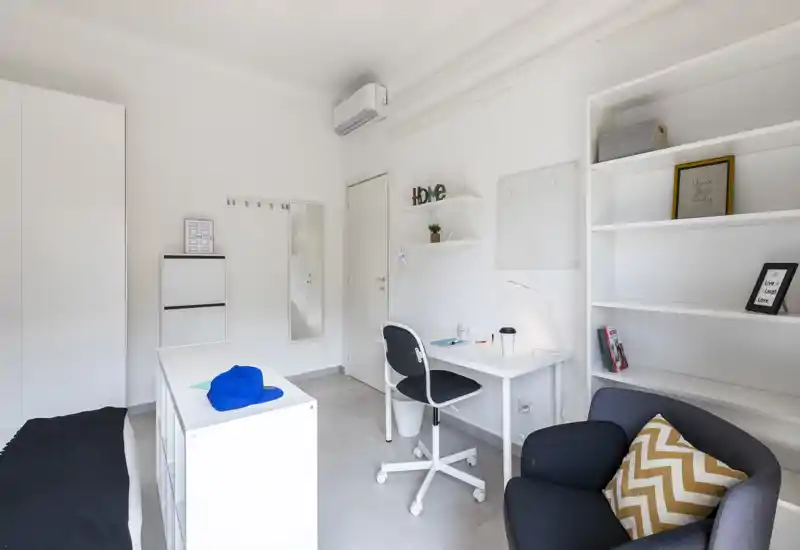 Dormitorio moderno y luminoso con cama individual, escritorio compacto y estanterías — espacio minimalista y bien iluminado, ideal para estudiantes o profesionales.