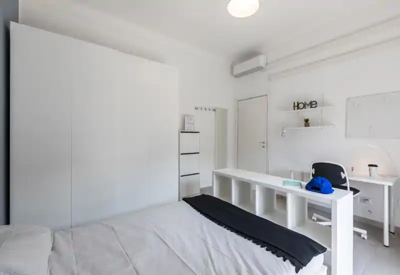 Dormitorio moderno y luminoso con cama ordenada, gran armario blanco y zona de estudio compacta — estilo minimalista ideal para el anuncio.