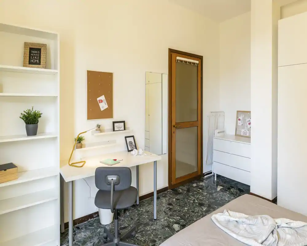 Rincón de dormitorio luminoso y ordenado con cama individual, escritorio compacto y estantería — ideal para estudiantes o profesionales que buscan un espacio de trabajo acogedor en la habitación.