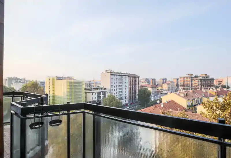 Balcone soleggiato con parapetto in metallo e pannelli di vetro, perfetto per la colazione e per godersi lo skyline cittadino.