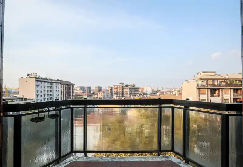 Balcone soleggiato con vista sulla città, ringhiera in metallo e vetro satinato e pavimento piastrellato — perfetto per il caffè mattutino e godersi lo skyline.
