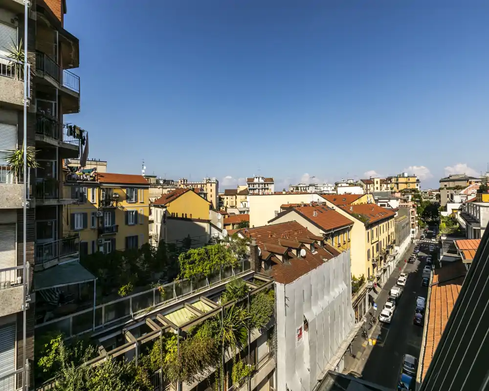 Vista soleada desde terraza/balcón con tejados y calle adyacente — cielo azul y panorámica urbana nítida, ideal para mostrar la ubicación y los alrededores.