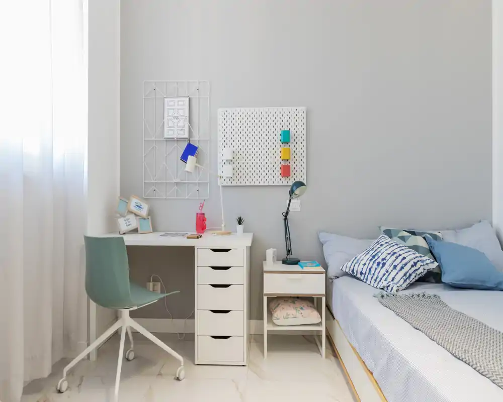 Bright, stylish bedroom with a comfortable bed, bedside table and a tidy desk by the window — ideal for rest and focused work.