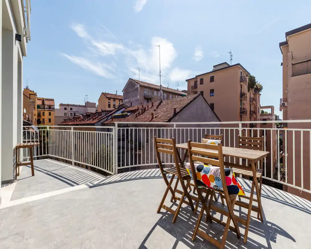 Sunny private terrace with foldable wooden table and chairs, city views and pleasant outdoor space ideal for dining or relaxing.