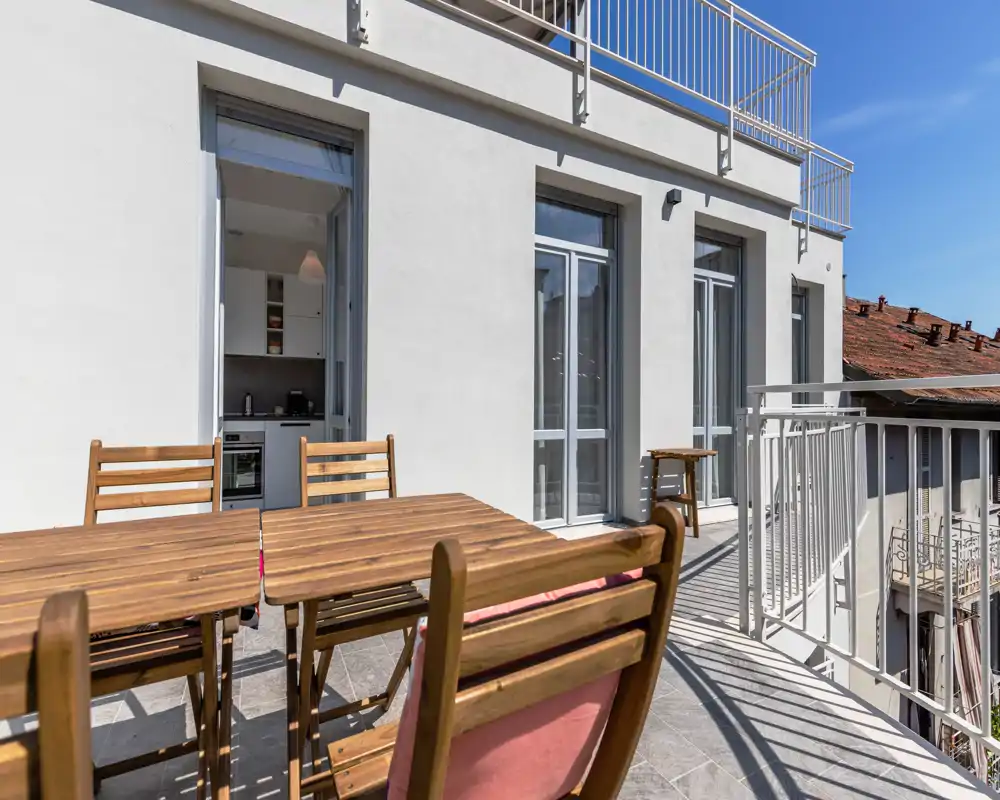 Sunny private balcony with wooden outdoor dining set, tiled floor and direct access to the kitchen — ideal for al fresco meals and morning coffee.