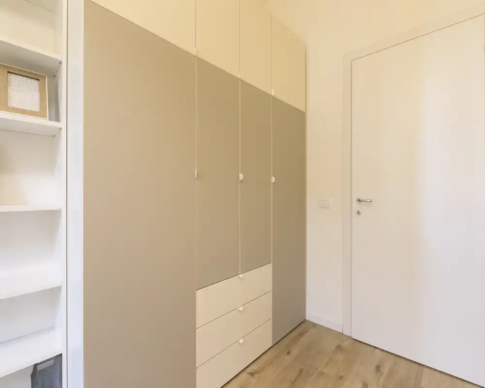 Dressing intégré et étagères dans un coin de chambre lumineux et minimaliste avec sol en bois et tons neutres.