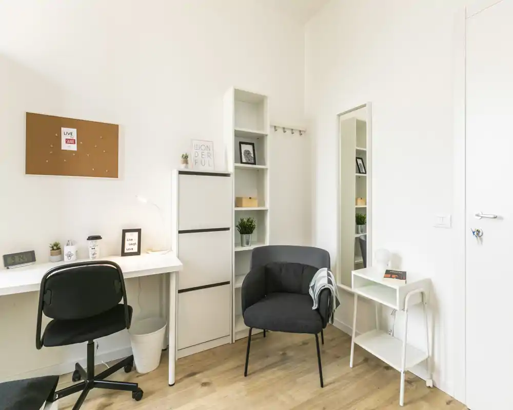 Rincón luminoso y moderno de salón/estudio con un sillón cómodo, escritorio y almacenaje minimalista — ideal para trabajar o descansar.