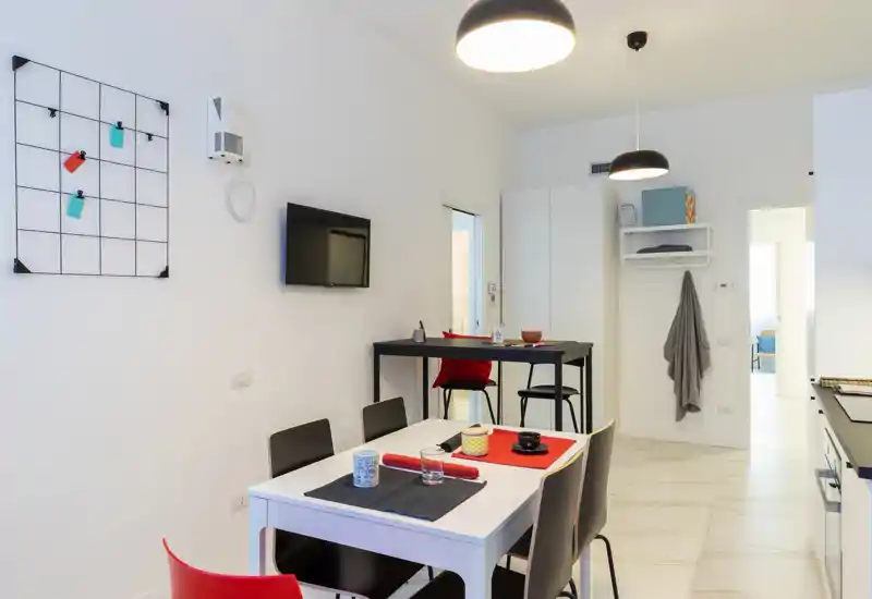 Stylish, bright living/dining area with a modern table setup, wall-mounted TV and tasteful accents; ideal for comfortable short stays.