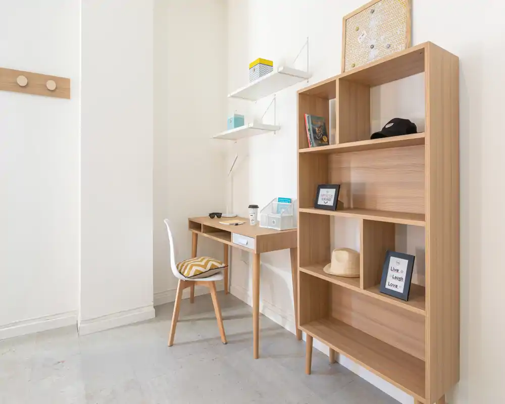 Bright and minimal study corner with a wooden desk, chair and open shelving — ideal for a compact home office.