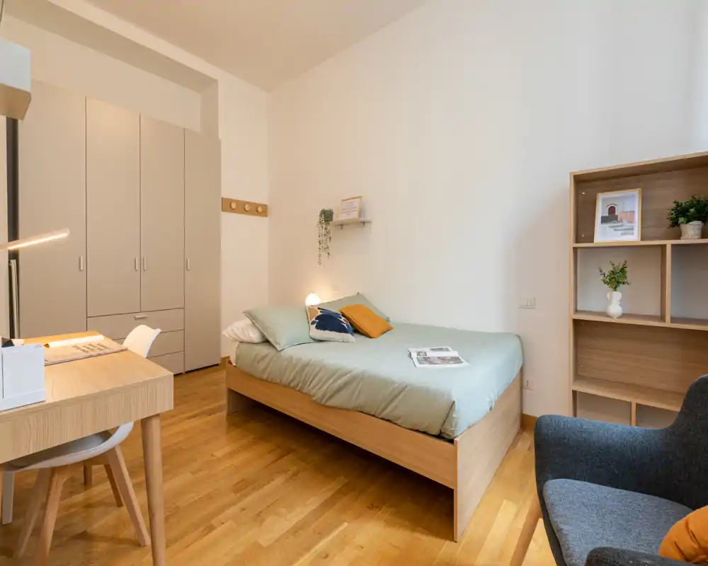 Chambre lumineuse et moderne avec un lit en bois complet, une literie verte, une armoire et un petit bureau — parfaite pour une location cosy.