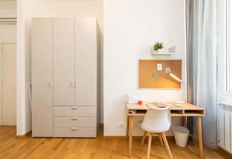 Bright, minimal bedroom corner with a large wardrobe and a compact wooden desk by the window, ideal for study or remote work.