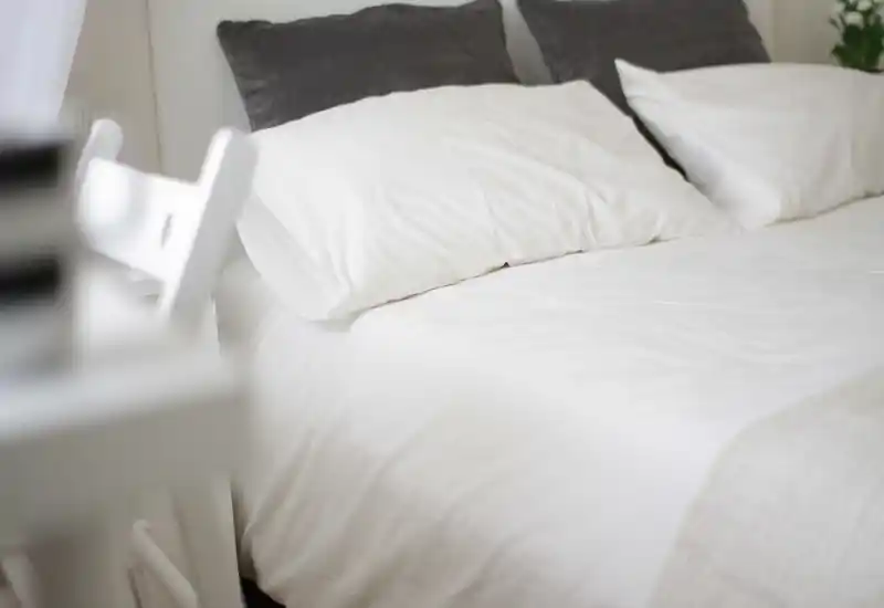 Bright, minimalist bedroom with crisp white linens, plush pillows and a clean, calm atmosphere — ideal for restful stays.