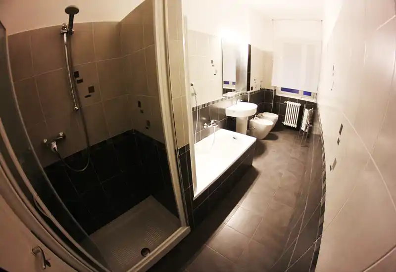 Modern bathroom with separate shower stall and bathtub, white sink and bidet; tiled walls and floor with contemporary fixtures.