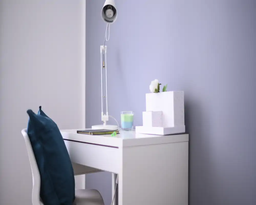 A tidy desk/reading corner with a modern white table, a lamp and decorative accents that create a calm, inviting space.
