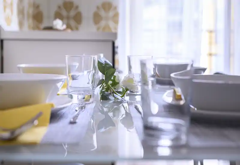 Well-styled dining table set with glassware, bowls and a floral centerpiece in bright natural light, ideal for showcasing the eating area of the property.