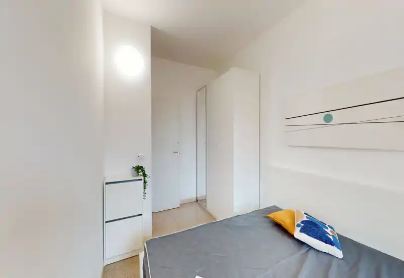 Camera minimalista con letto matrimoniale, armadio semplice e pareti neutre. Ambiente luminoso e ordinato, adatto per affitti brevi.