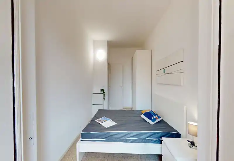 Camera da letto luminosa e minimal con letto matrimoniale, comodino e armadio. Linee pulite e arredi neutri rendono la stanza fresca e ordinata.