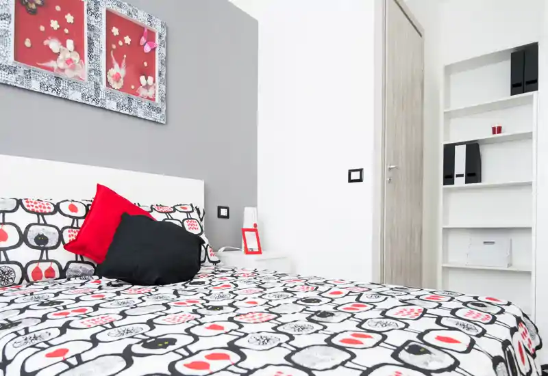 Bright, modern bedroom with patterned bedding, decorative pillows and a white headboard. Clean styling and natural light make it inviting for listings.