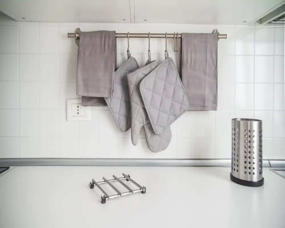 Encimera de cocina minimalista y luminosa con agarraderas colgadas y portautensilios ordenado: un área de cocina limpia y funcional.