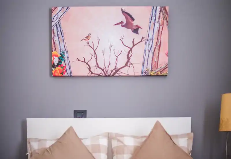 Cozy bedroom headboard with patterned pillows and decorative wall art above; soft, even lighting creates a warm, inviting atmosphere.